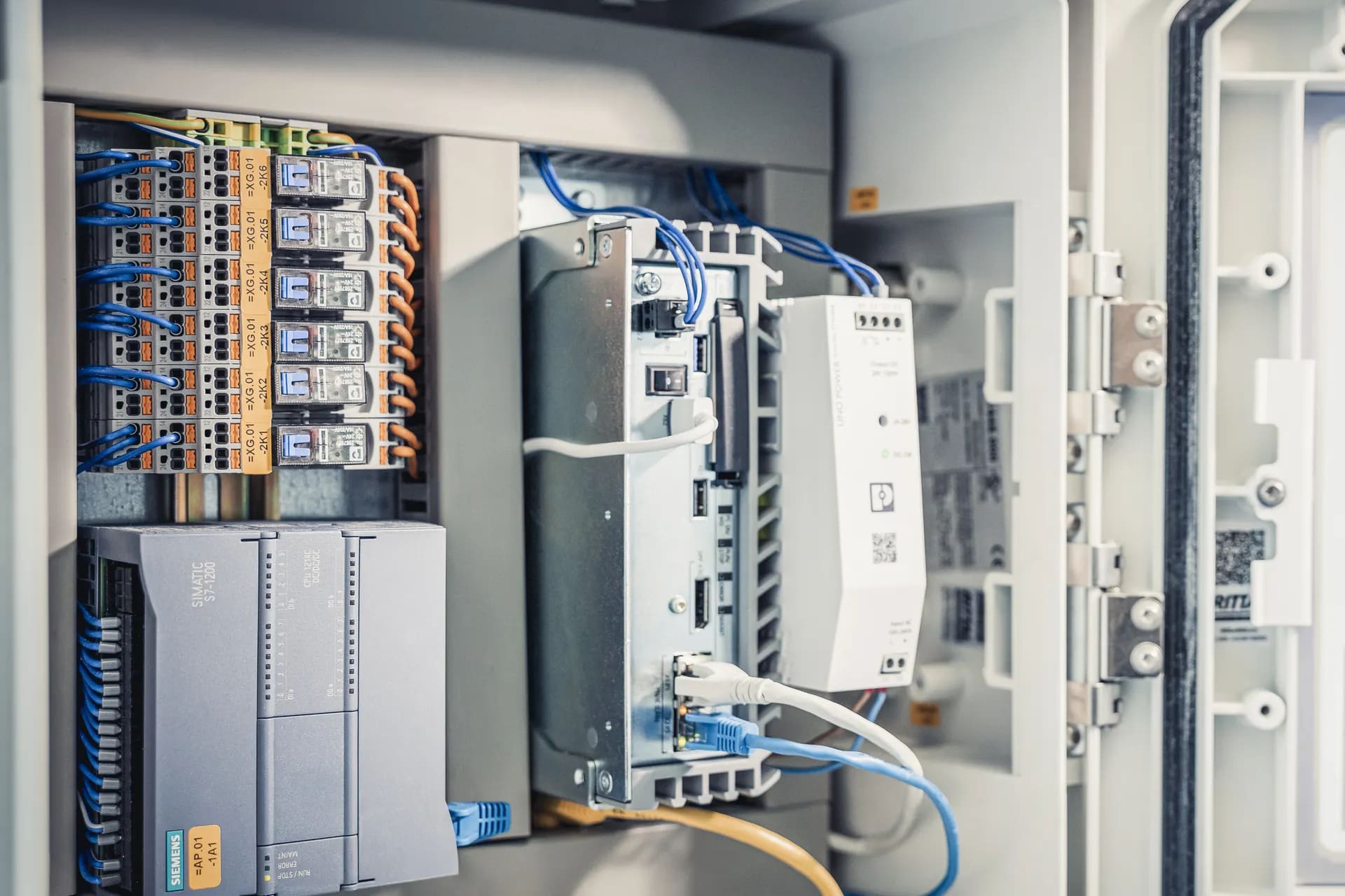 Geöffneter Schaltschrank der Gebäudeautomation mit Steuerung, Relais und Netzwerkanschlüssen.